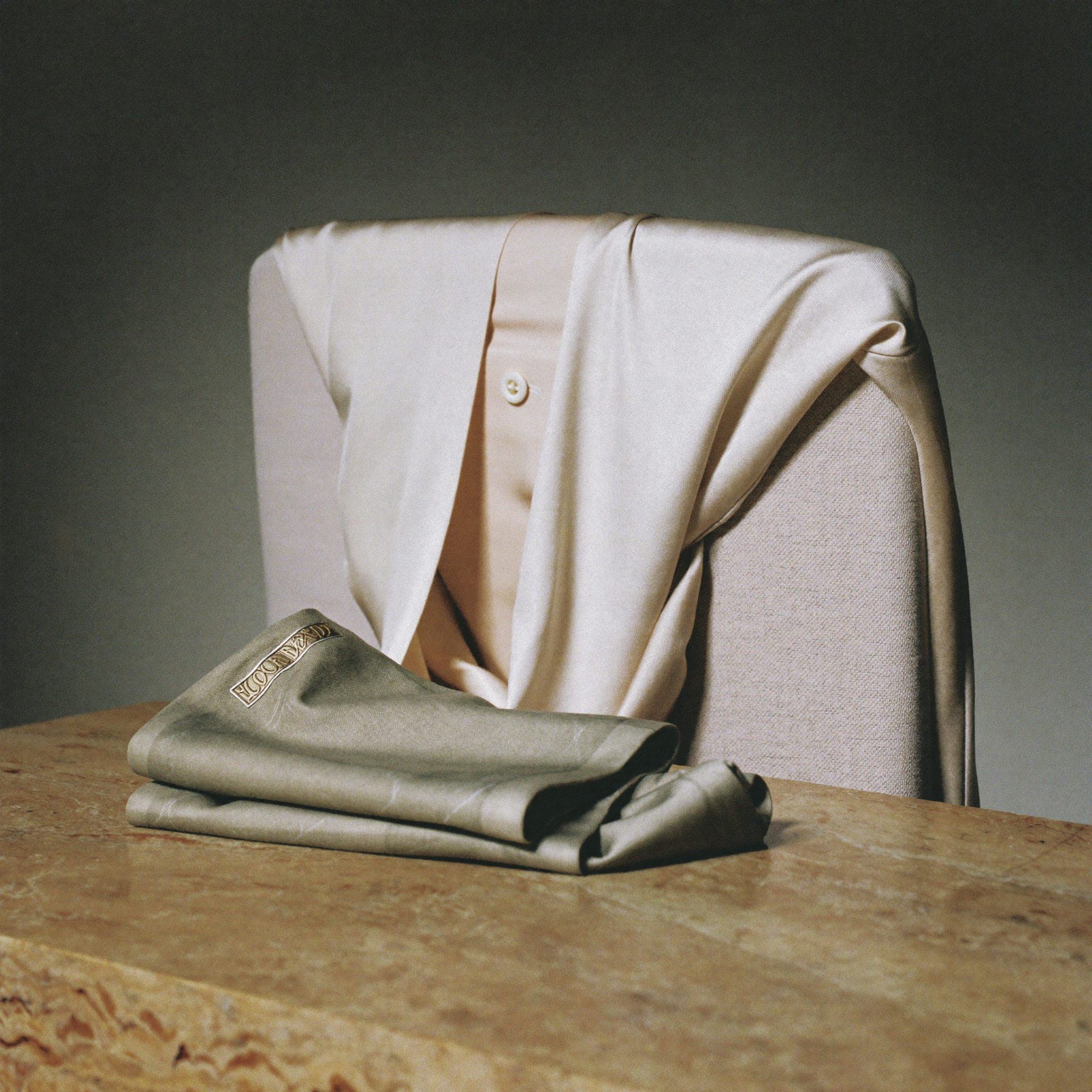 Ivory silk blouse draped over a linen chair with a sage scarf
